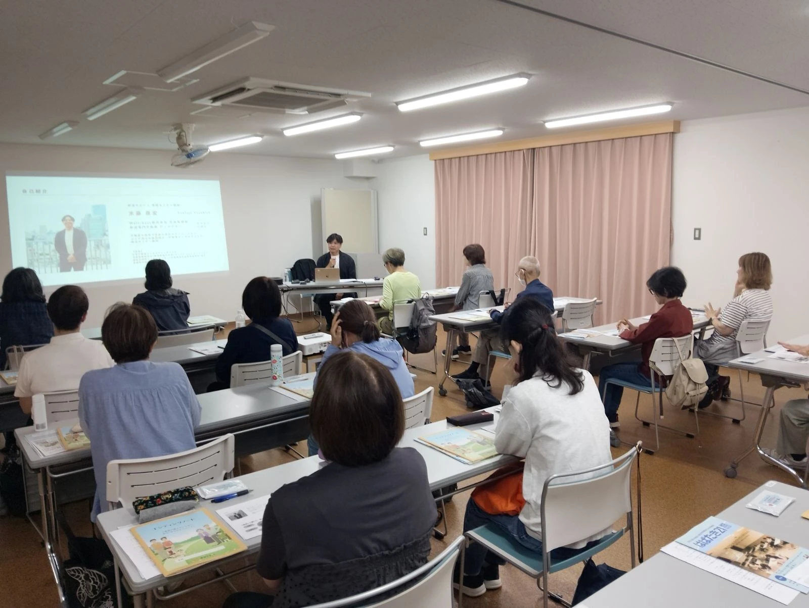 終活講座で自己紹介をする講師と、机に資料を広げた参加者